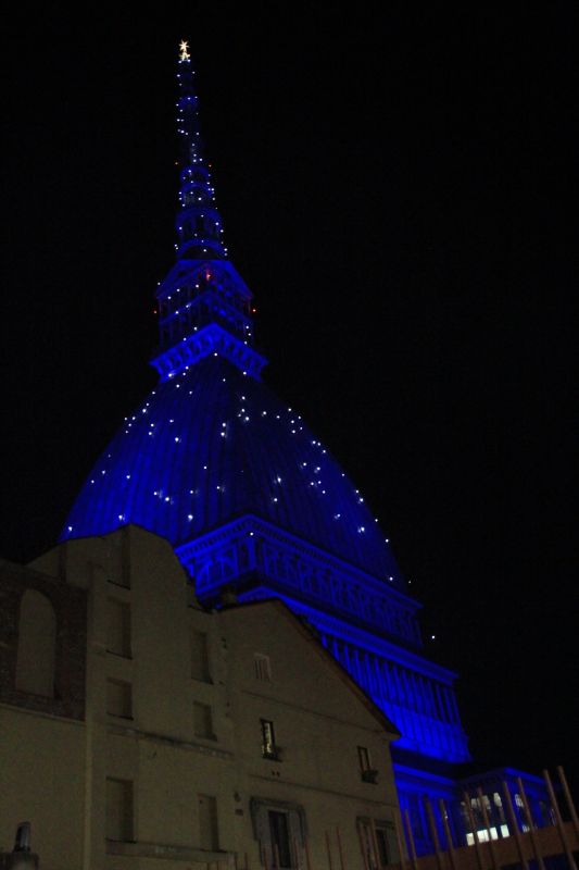 Torino, la cupola della Mole Antonelliana si illumina di blu tra gli edifici del centro. Foto di Stefano Borghini [CC BY NC SA]