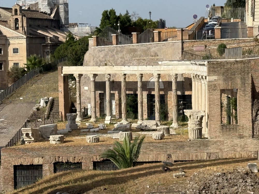 Portico degli Dei Consenti, veduta dal Foro Romano. Il complesso, disposto ai piedi del Campidoglio accanto al Tempio del Divo Vespasiano, comprende un portico colonnato e una serie di ambienti retrostanti. Restaurato nel 367 d.C. per iniziativa del prefetto urbano Vettio Agorio Pretestato, deve il suo aspetto attuale anche alla ricostruzione ottocentesca del 1858, realizzata rialzando elementi antichi e introducendo integrazioni moderne [Foto: Maria Teresa Natale, CC BY-NC-SA]